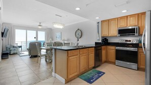 A modern kitchen with wooden cabinets, stainless steel appliances, and a large island. - Grandview East 304 (Panama City Beach)