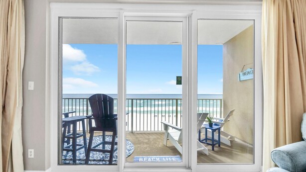 A room with a sliding glass door leading to a balcony with a view of the beach. - Grandview East 302 - Sandscape (Panama City Beach)