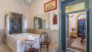 A spacious bathroom with a large bathtub, a mirror, and a wooden chair.