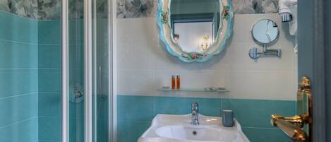 A bathroom with a glass shower enclosure, a white sink with a mirror, and a towel rack.