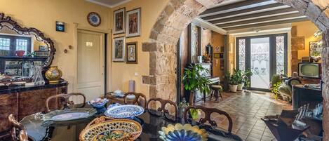 A dining area with a stone archway, a dining table with various dishes, and a television in the background.