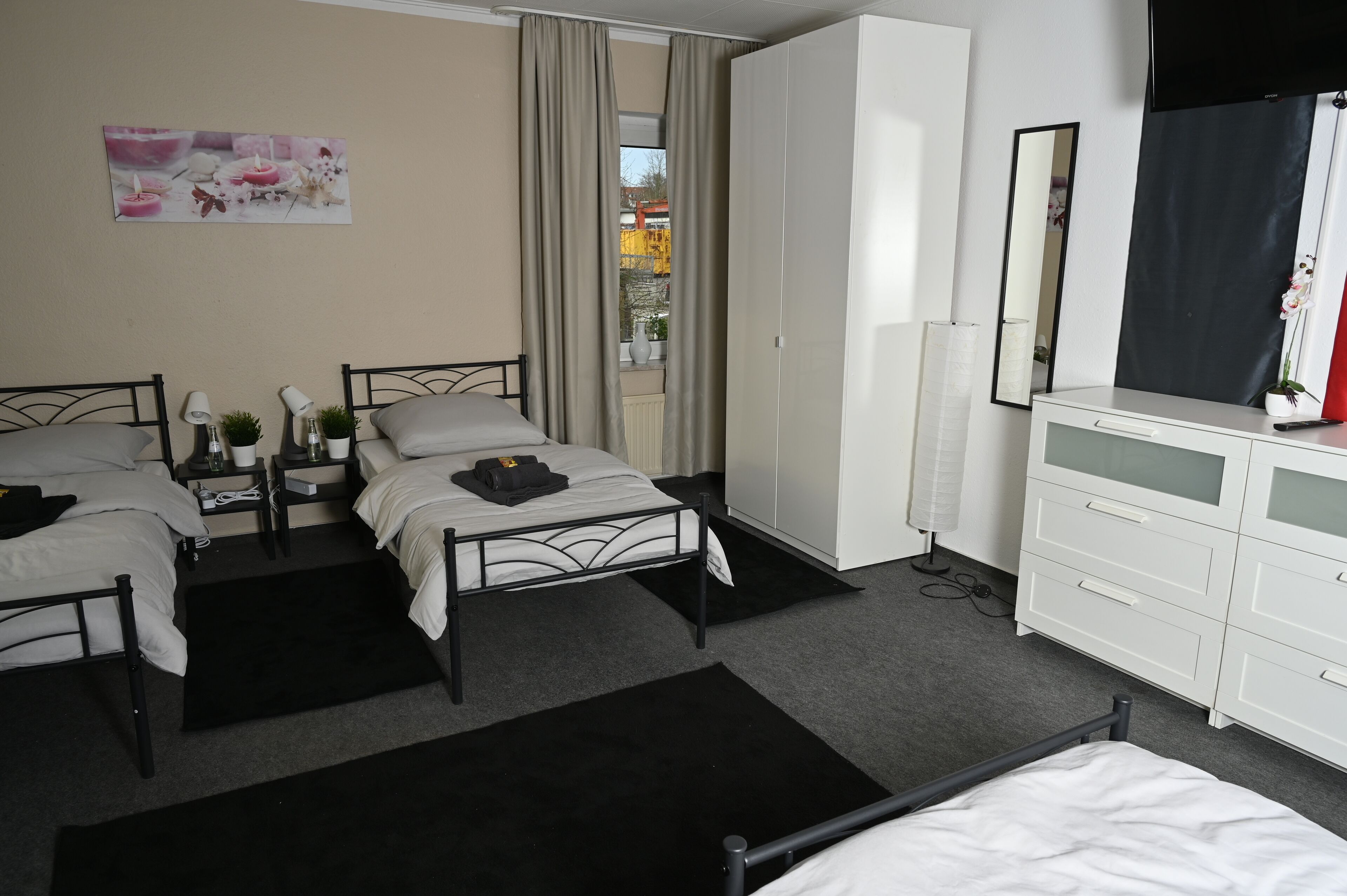 Ein Hotelzimmer mit zwei Betten, einem weißen Schminktisch, einem Spiegel und einem Fenster mit Vorhängen.