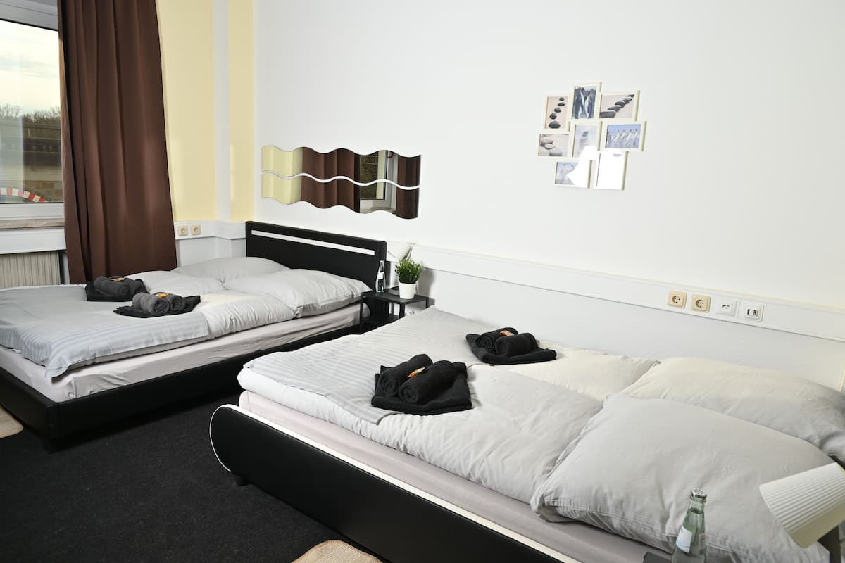 A hotel room with two beds, a small table with a plant, and a wall with framed pictures.