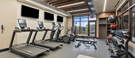 A modern gym with treadmills, stationary bikes, and weight machines.