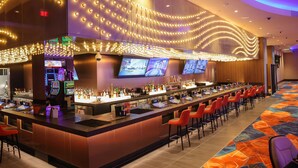 A hotel bar with a long counter, multiple screens, and a carpeted floor. - Spokane Tribe Resort and Casino (Airway Heights)