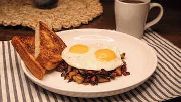 Ein Teller mit Eiern, Toast und Hash Browns auf einer gestreiften Serviette.