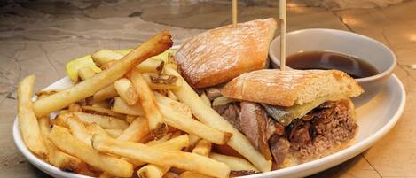 A plate with a sandwich, fries, and a small bowl of sauce.