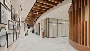 A modern hotel lobby with a curved wooden reception desk, framed photographs on the walls, and a tiled floor. - Spokane Tribe Resort and Casino (Airway Heights)