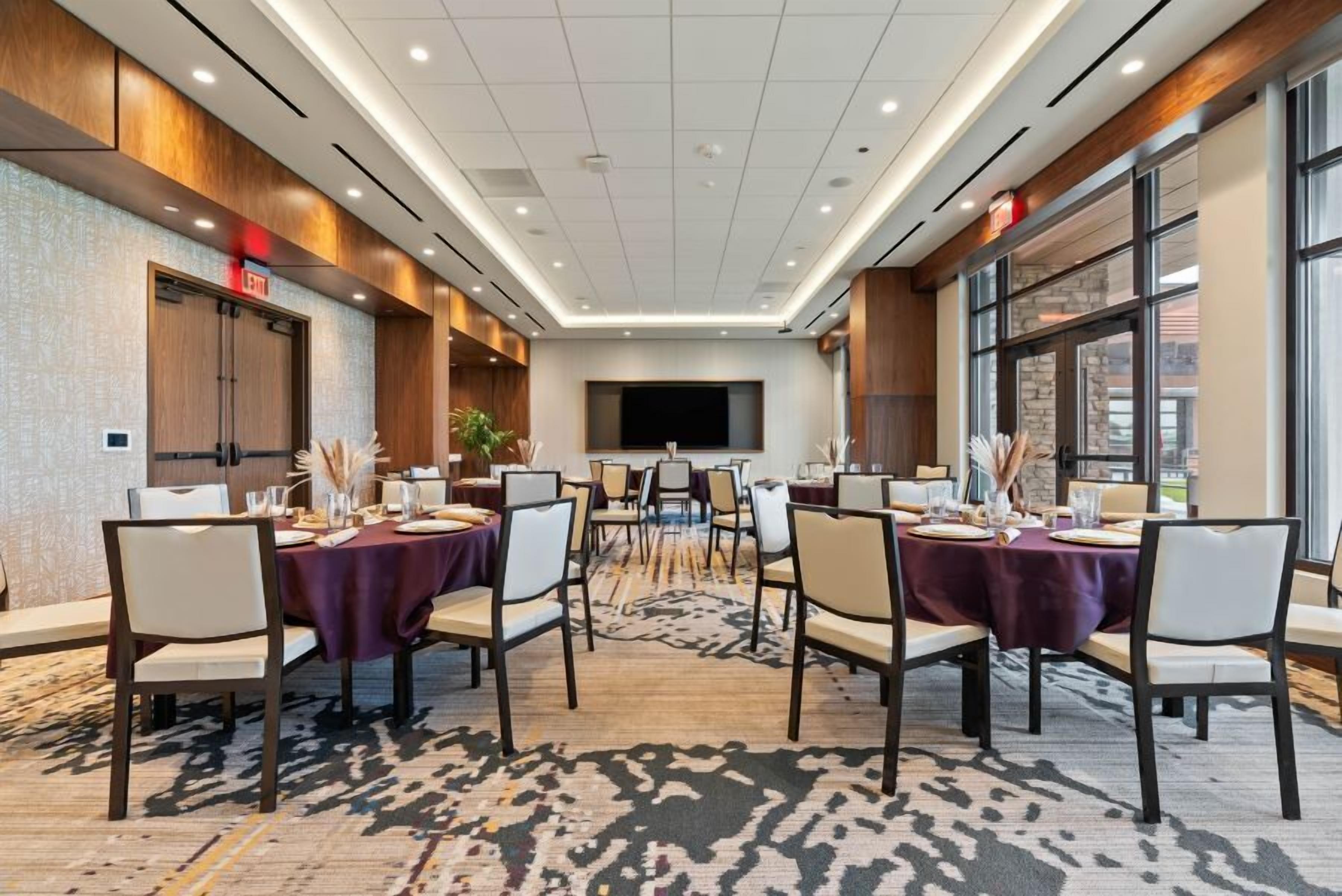 A conference room with a large table, multiple chairs, and a television screen.