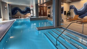 An indoor swimming pool with clear lanes, a changing room area, and a seating area with lounge chairs. - Spokane Tribe Resort and Casino (Airway Heights)