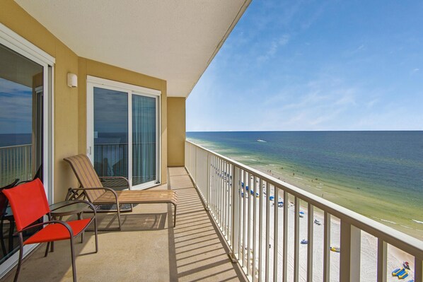 A balcony with a view of the beach, a chair, and a table. - Grandview East 1204 (Panama City Beach)