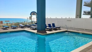 Una piscina con sillas de descanso, una torre de salvavidas y vistas a la playa.