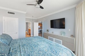 A bedroom with a bed, a ceiling fan, a TV, and a dresser.