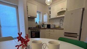 A modern kitchen with white cabinets, a white refrigerator, a microwave, and a stove. There is a table with two mugs labeled "His" and "Her". - Serelor Apartment Free Parking (Dumbrăvița)