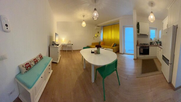 A compact living space with a dining area, kitchenette, and a sofa. - Serelor Apartment Free Parking (Dumbrăvița)
