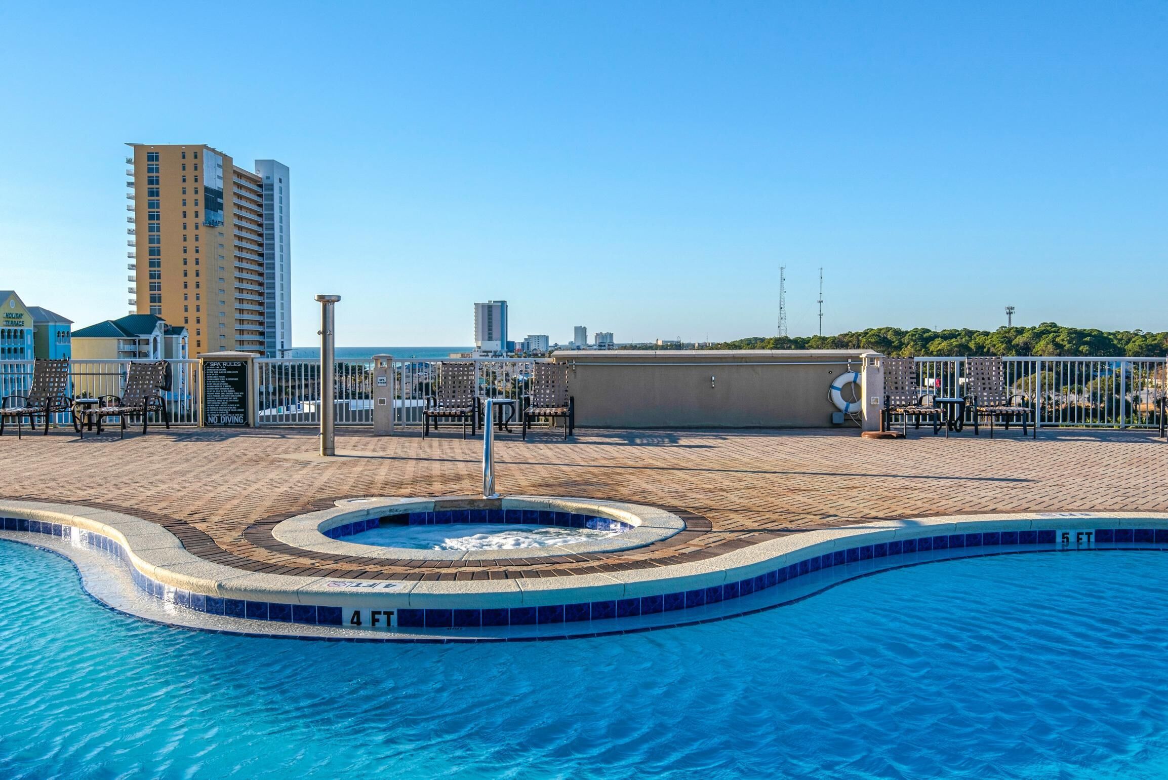 Ein Pool auf dem Dach mit Whirlpool, Liegestühlen und Blick auf die Skyline der Stadt.