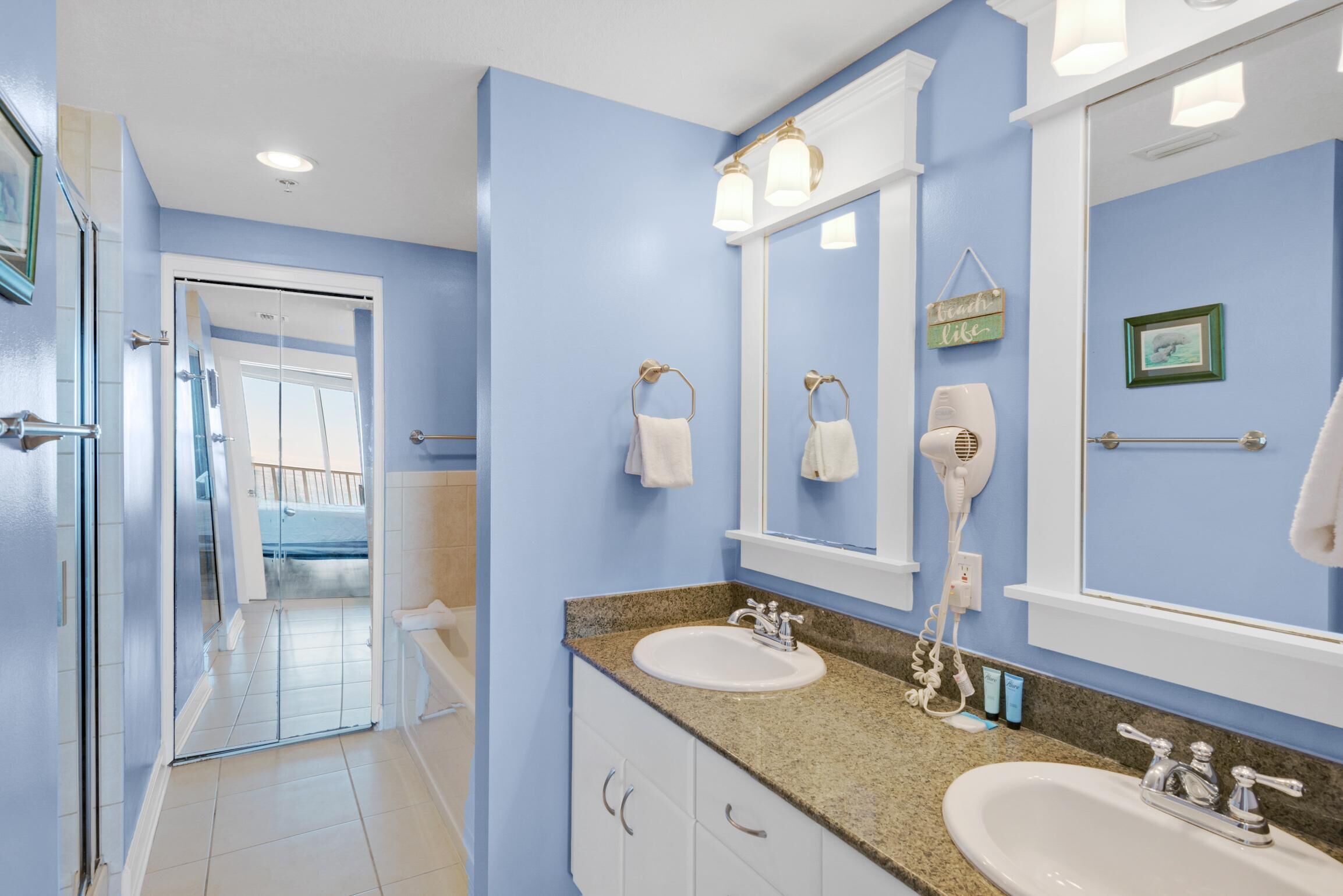 A bathroom with two sinks, a large mirror, and a hairdryer.