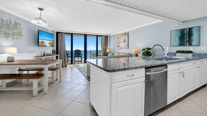 A modern kitchen with white cabinetry, a granite countertop, and a stainless steel dishwasher. - Edgewater Tower 2-408 (Panama City Beach)