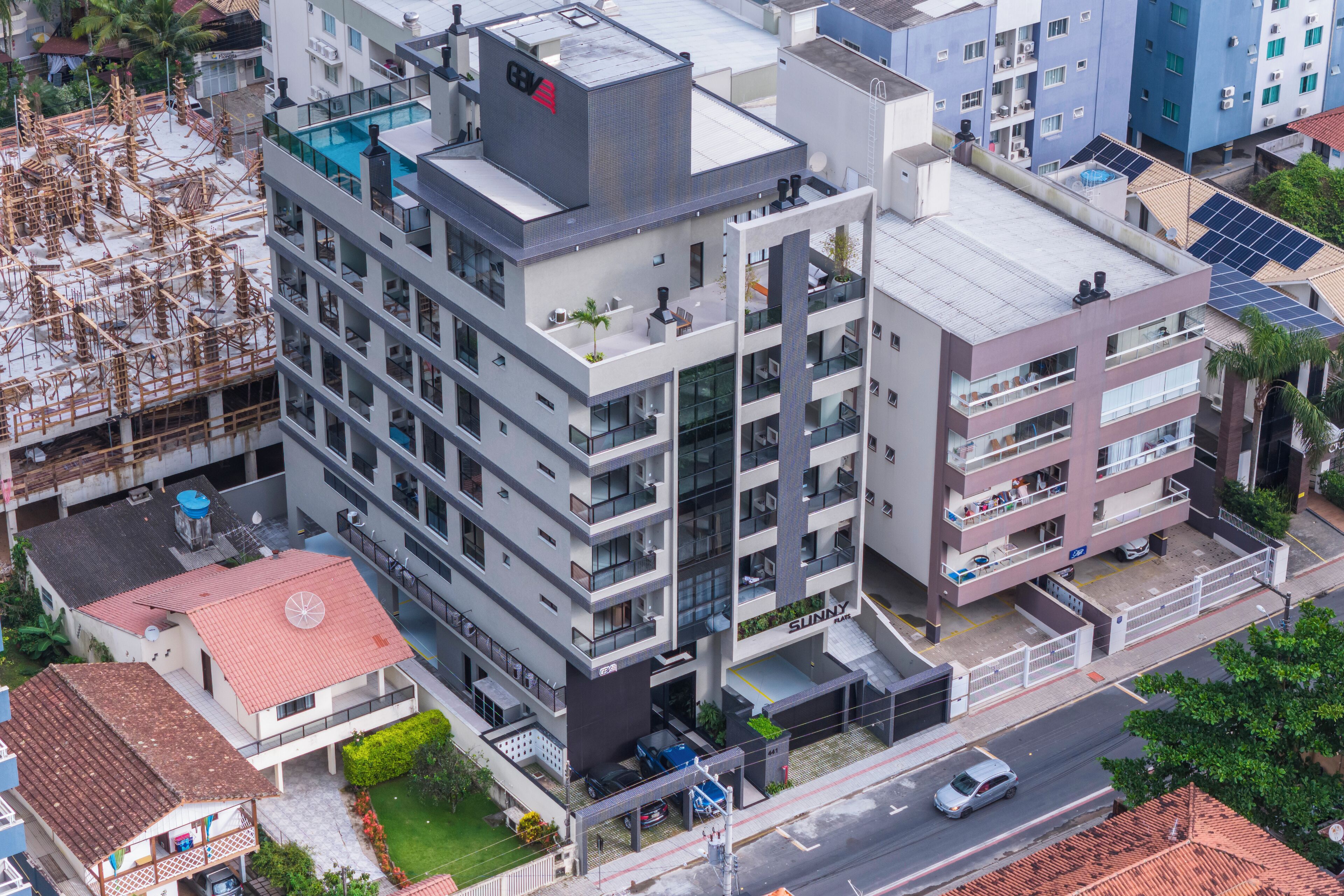 Un hotel de varios pisos con balcones, piscina en la azotea y paneles solares.