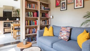 Un salon avec un canapé gris, des coussins jaunes et une bibliothèque remplie de livres.