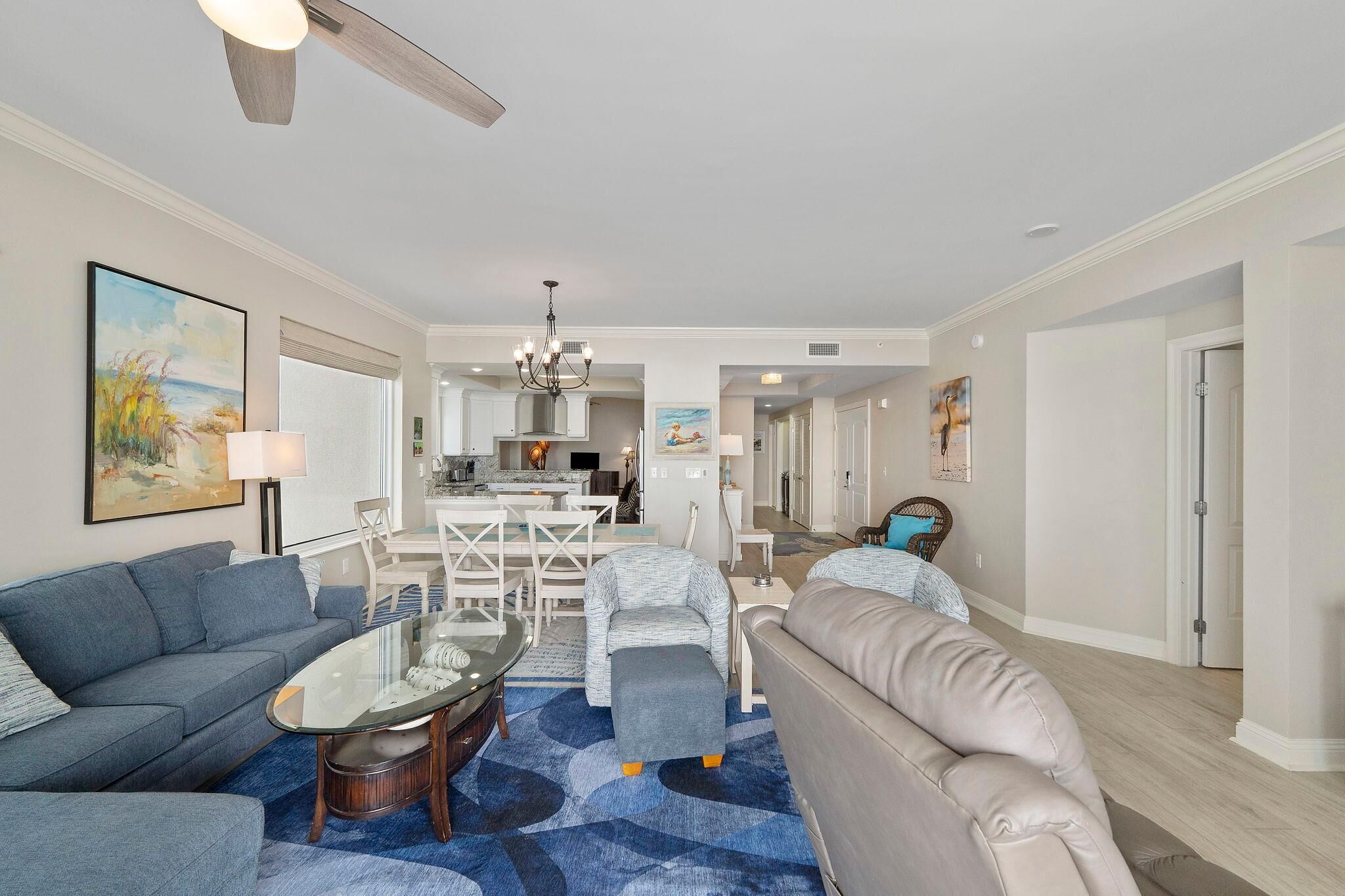 A spacious living room with a sofa, armchair, and coffee table. A dining area with a table and chairs is visible in the background.