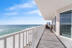 A balcony with a view of the ocean, a white railing, and a seating area with chairs and a table. - Windemere 708 (Pensacola)