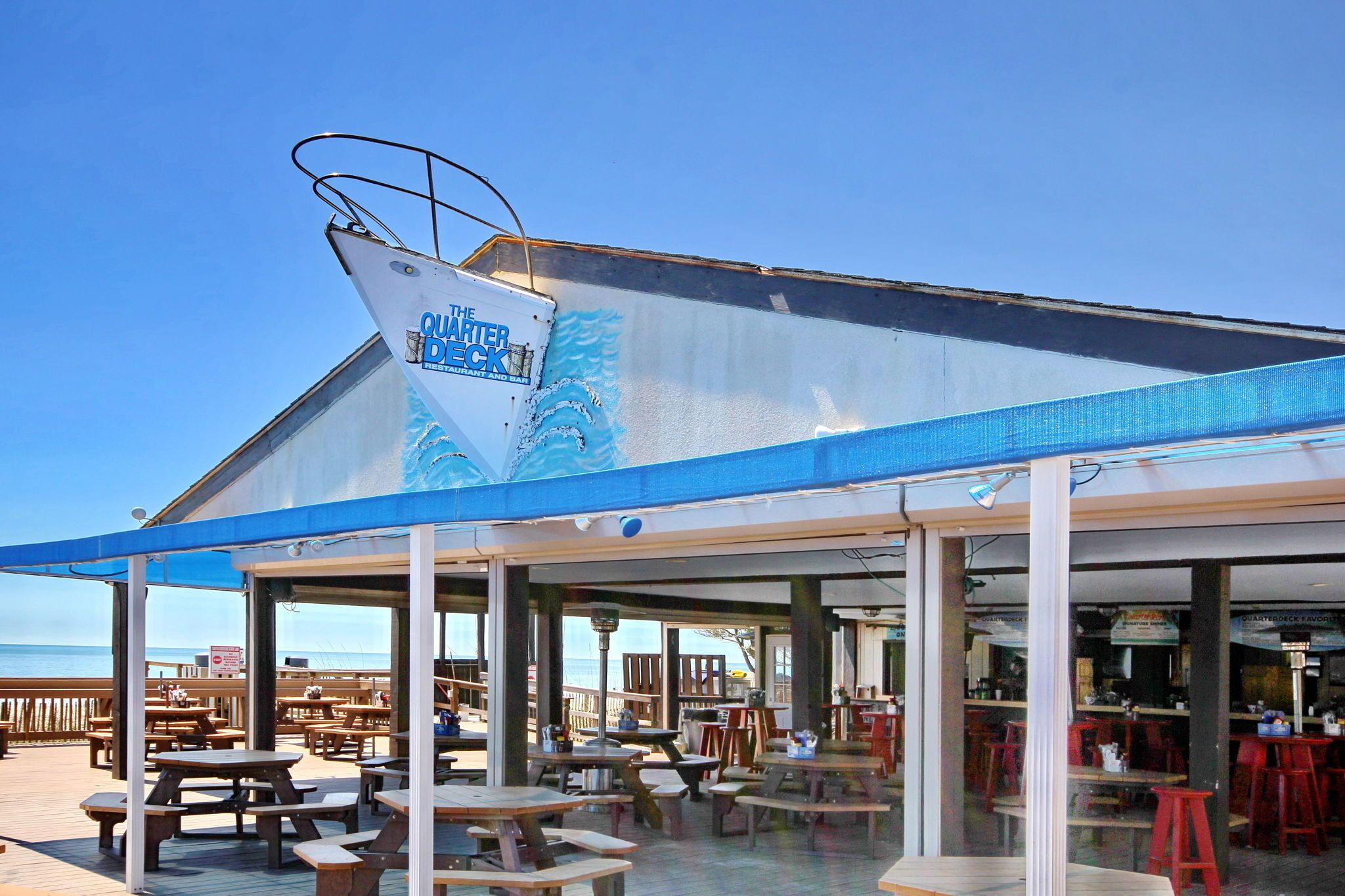 Ein Restaurant im Freien mit einer blauen Markise und einem Schild mit der Aufschrift 'QUARTER DECK'.