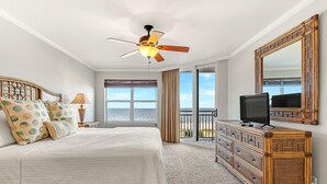Ein Schlafzimmer mit Bett, Fernseher, Kommode und einem Balkon mit Aussicht.
