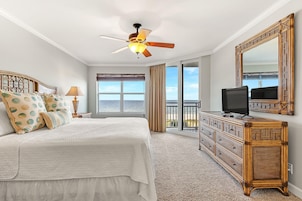 A bedroom with a bed, a television, a dresser, and a balcony with a view.