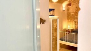 Una habitación con techo de piedra, una cama con estructura blanca y una lámpara colgante.