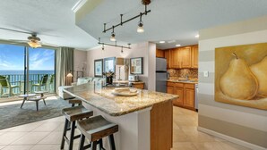 A spacious kitchen with a large island, wooden cabinets, and a view to the outside. - Perdido Towers West 907 (Pensacola)