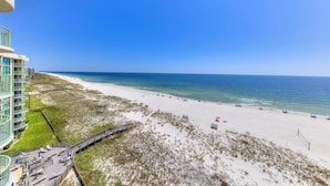 A beachside hotel with a boardwalk leading to the beach, a pool area, and a view of the ocean. - Perdido Towers West 907 (Pensacola)