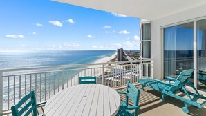 A balcony with a view of the beach and ocean, featuring a table and chairs. - Palacio 1803 (Pensacola)