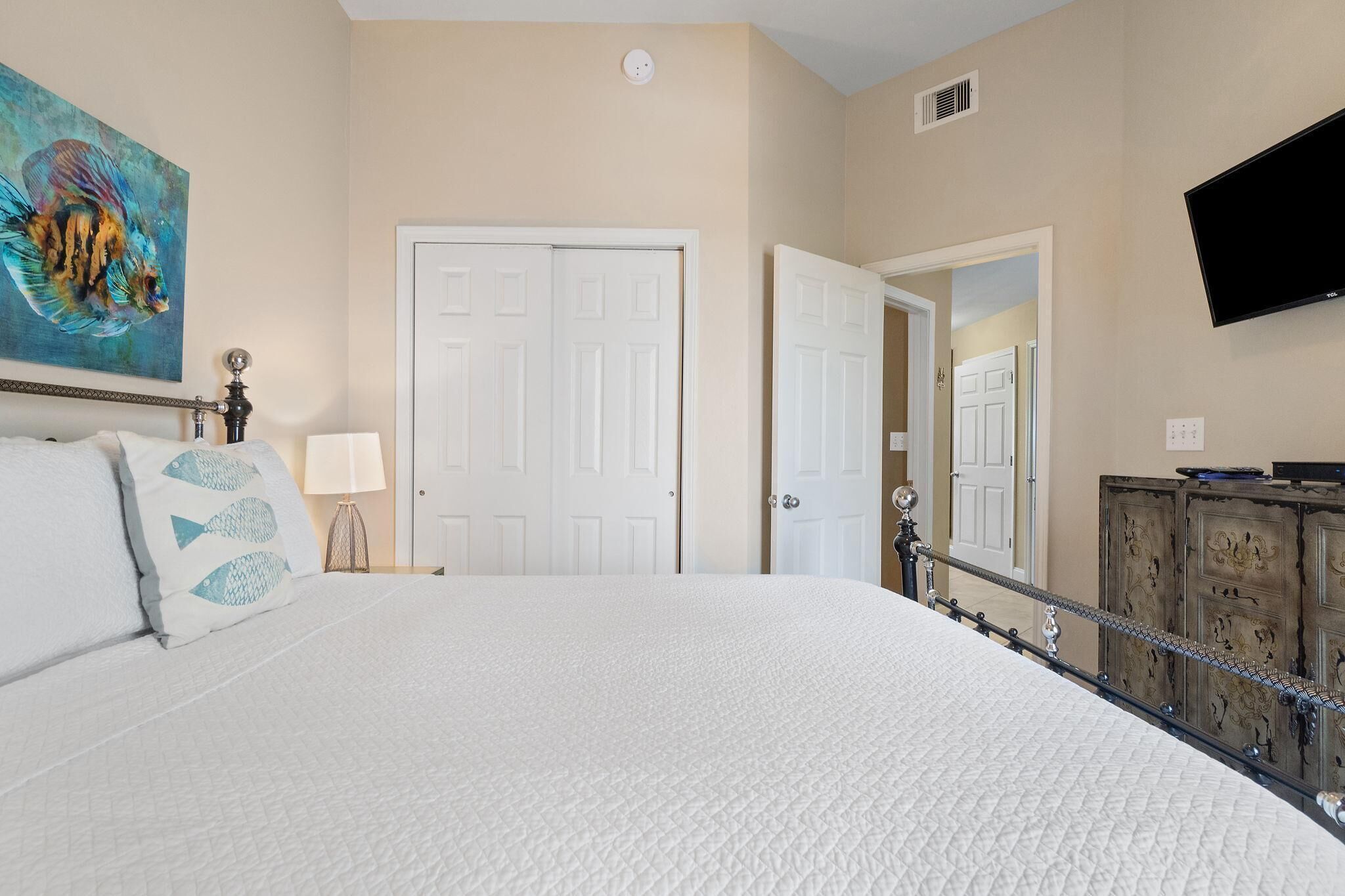A bedroom with a bed, a painting, a TV, and a wardrobe.