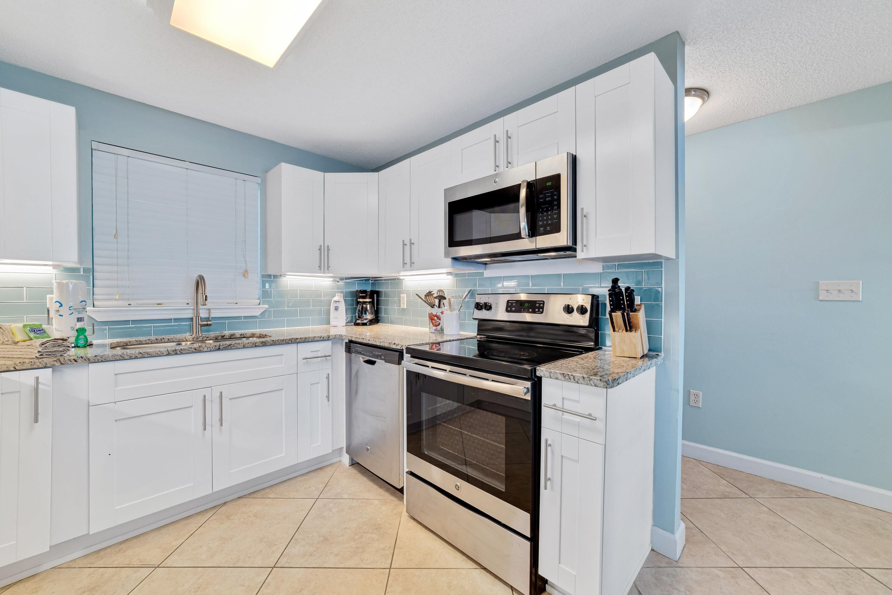 A modern kitchen with white cabinets, a stainless steel microwave, a built-in oven, and a granite countertop.