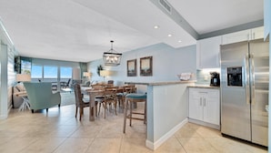 A spacious kitchen with a central island, stainless steel appliances, and a dining area with bar stools. - Sandy Key 631 (Pensacola)
