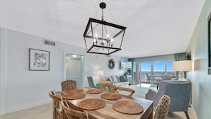 A dining area with a wooden table, woven placemats, and wicker chairs. - Sandy Key 631 (Pensacola)