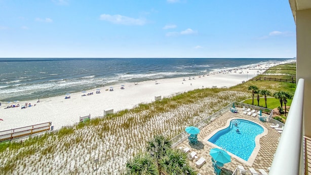 A beach view with a swimming pool and lounge chairs. - Sandy Key 631 (Pensacola)