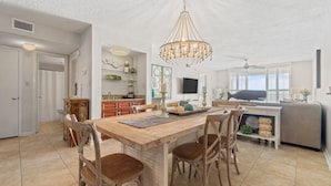 A spacious living area with a wooden dining table, four chairs, and a chandelier. - Summerchase 1107 (Orange Beach)