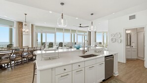 A spacious kitchen with a large island, white cabinetry, and a view of the ocean. - Vista Del Mar 305 (Pensacola)