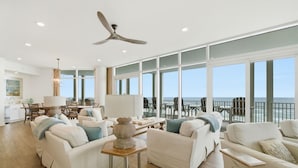 A spacious living room with a view of the ocean, white furniture, and a ceiling fan. - Vista Del Mar 305 (Pensacola)