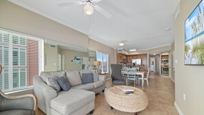 A spacious living room with a grey sofa, a round wicker ottoman, and a ceiling fan. - Tidewater 609 (Orange Beach)
