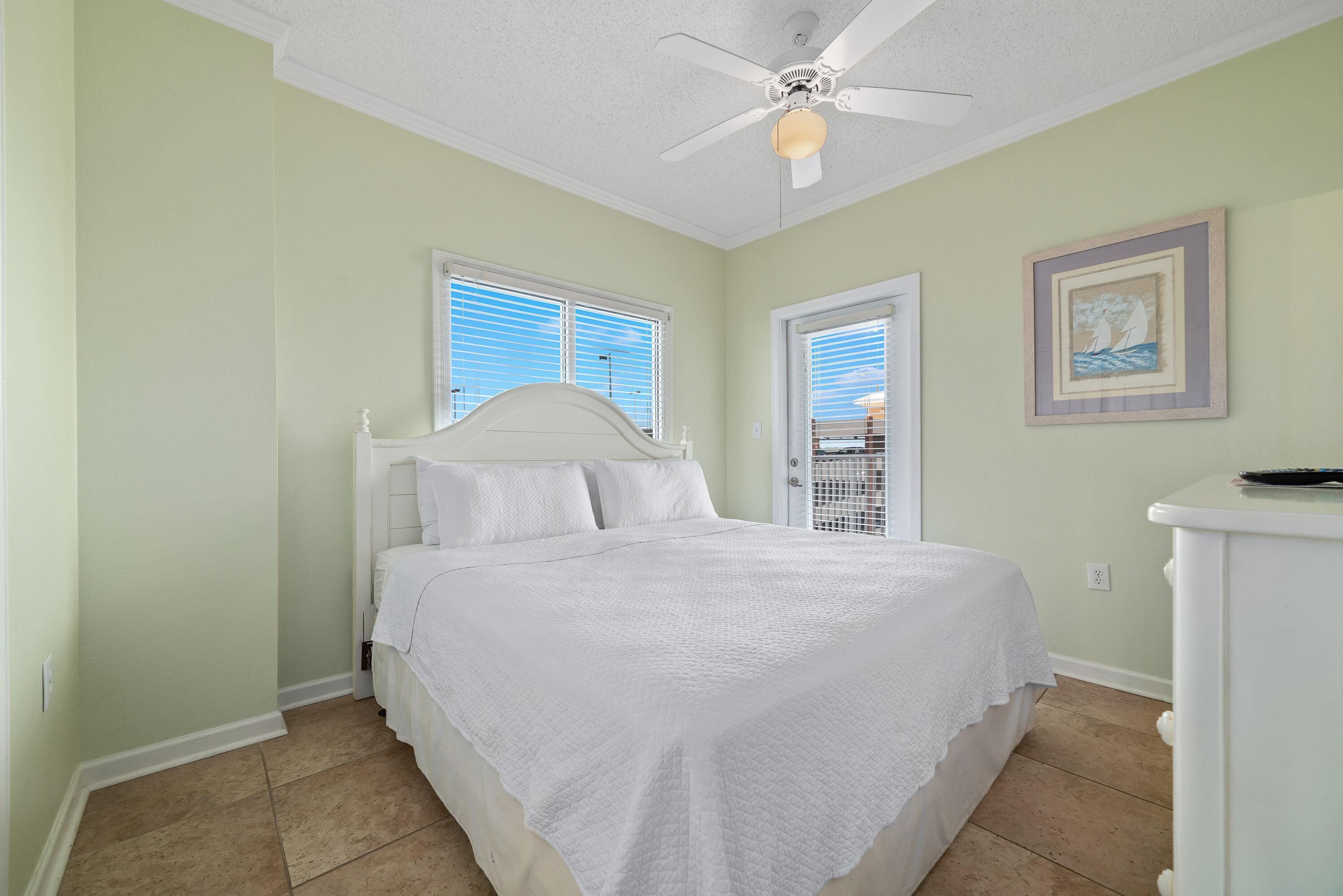 A bedroom with a bed, a ceiling fan, and a door.