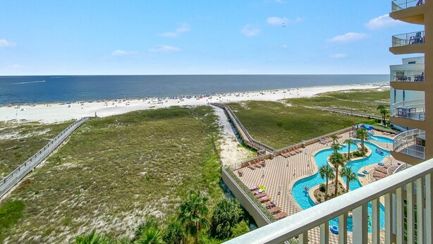 A beach view from a balcony overlooking a resort area with a pool and beach amenities. - Tidewater 609 (Orange Beach)