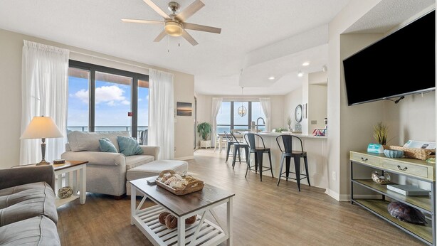 A modern living room with a sofa, coffee table, and a dining area with chairs. - Seachase 404e (Orange Beach)