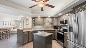 A modern kitchen with a central island, stainless steel appliances, and a ceiling fan. - Summer House 203a (Orange Beach)