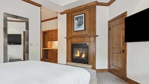 Ein Schlafzimmer mit einem großen Bett, einem Kamin, Holzschränken und einem Fernseher.