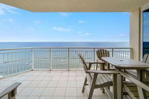 A balcony with a view of the ocean, a table, and two chairs. - Indigo East 1801 (Pensacola)
