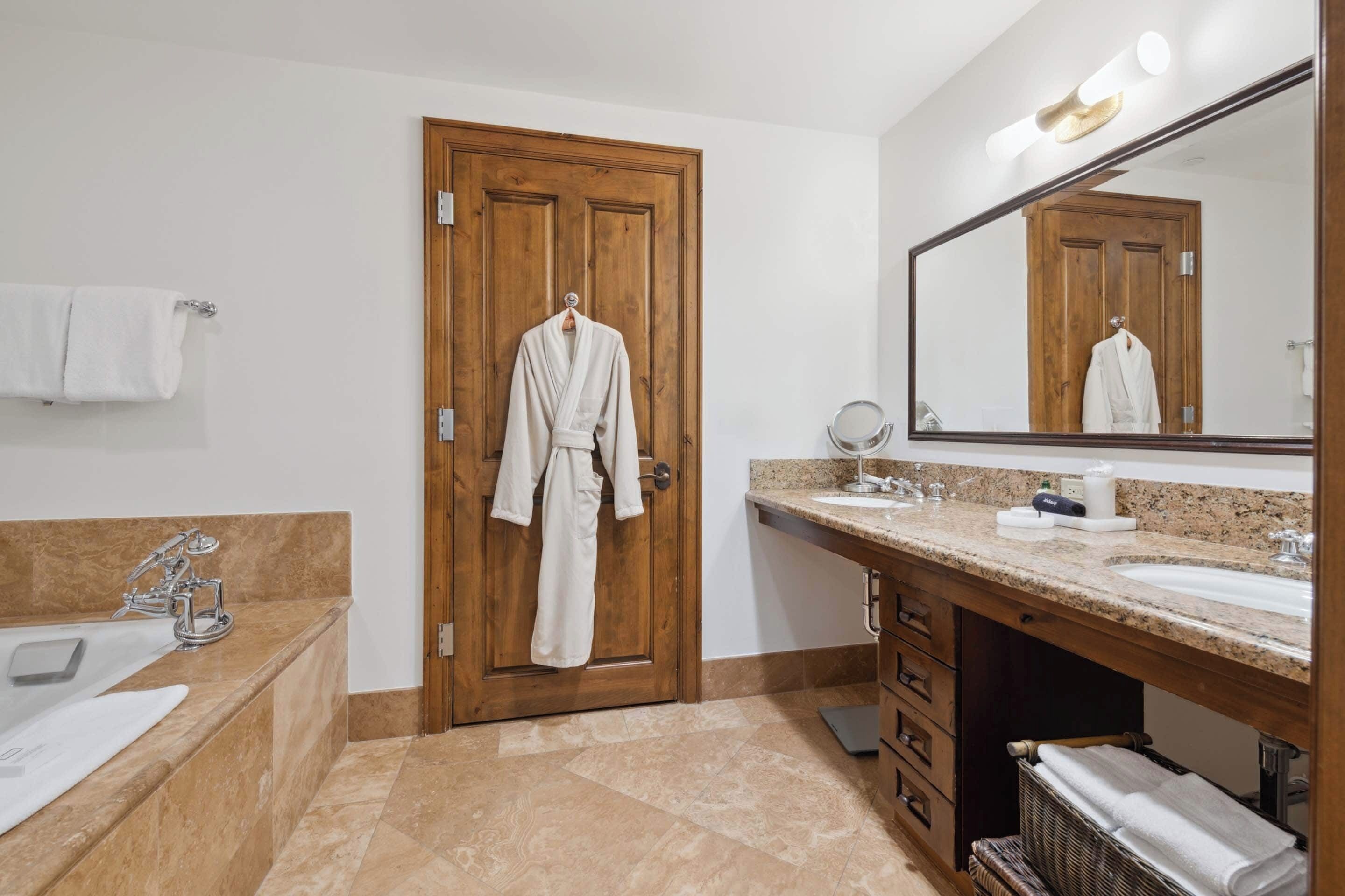 Un bagno con porta in legno, un lavandino, una vasca e uno specchio grande.