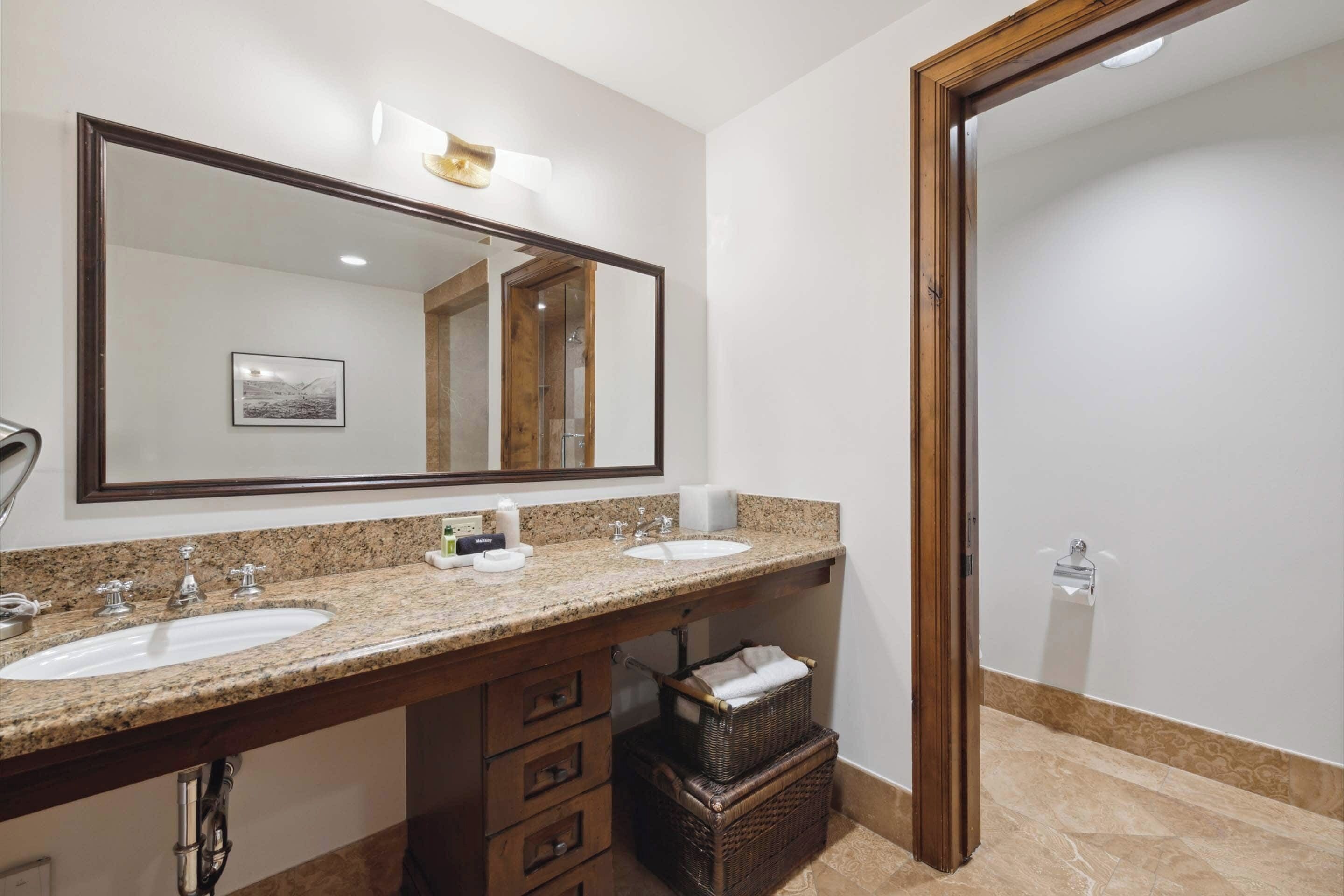A bathroom with two sinks, a large mirror, and a wooden door.